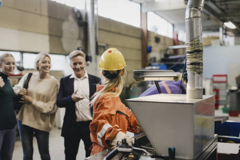 Älterer Geschäftsmann und Familie im Gespräch mit einer Arbeiterin in einer Fabrik - MASF28237