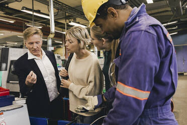 Male worker in protective workwear discussing with businessman and family in industry - MASF28241