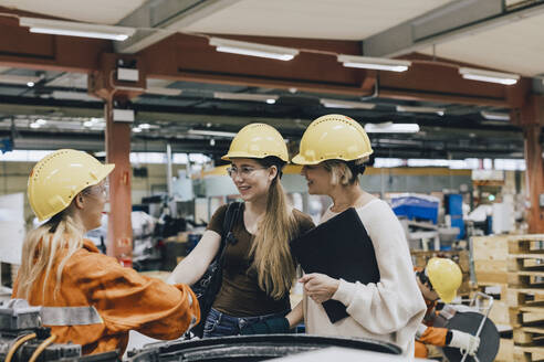Lächelnde Geschäftsfrauen im Gespräch mit einer Arbeiterin in einer Fabrik - MASF28252