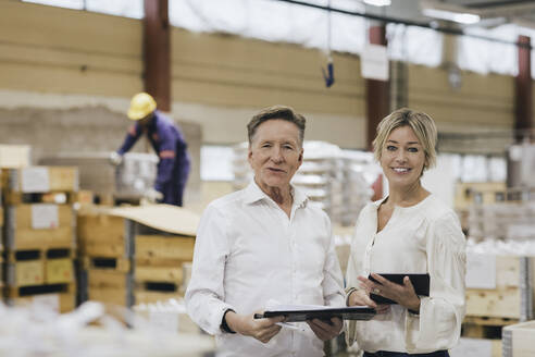 Porträt eines älteren Geschäftsmannes mit Tochter in einem Fabriklager - MASF28261