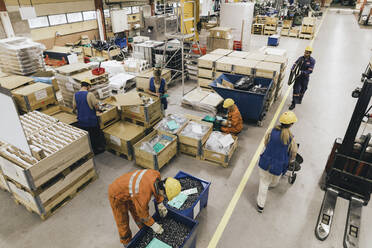 Männliche und weibliche Arbeiter in Uniform arbeiten in einem Fabriklager - MASF28264