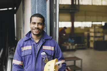 Porträt eines selbstbewussten männlichen Arbeiters in Arbeitsschutzkleidung in einer Fabrik - MASF28281