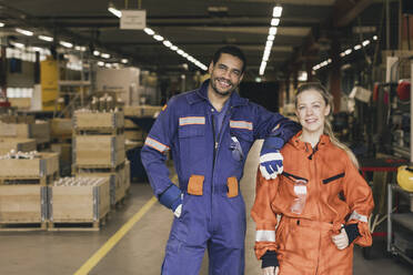 Porträt eines lächelnden männlichen und weiblichen Mitarbeiters in einem Fabriklager - MASF28284