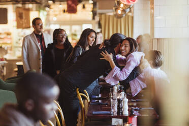 Männliche und weibliche Freunde verschiedener Rassen grüßen im Restaurant nach der Arbeit - MASF28334