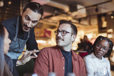 Kellner im Gespräch mit Freunden im Restaurant während des Abendessens - MASF28338