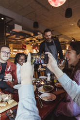 Ausgeschnittenes Bild eines Mannes, der mit seinem Mobiltelefon in einer Bar ein Foto von einem Mann und einer Frau macht - MASF28349
