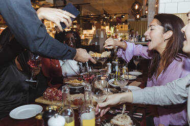 Cropped image of waiter serving food and drinks to customers at table - MASF28352