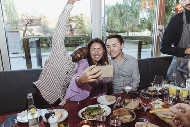 Frau macht Selfie mit männlichen Freunden beim Feiern in einer Bar nach der Arbeit - MASF28353