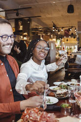 Male and female friends having dinner during part at restaurant - MASF28354