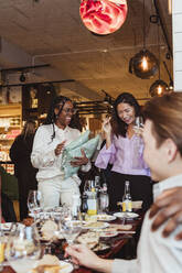 Multiracial female friends laughing while celebrating during dinner party - MASF28365