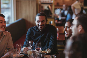 Glücklich multirassische männliche und weibliche Freunde mit Wein in einem Restaurant - MASF28372