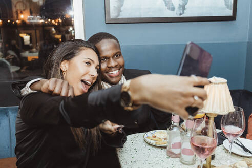 Young male and female friends taking selfie through smart phone at bar - MASF28389