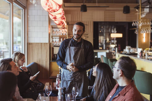 Multiracial customers ordering food from waiter in restaurant - MASF28406