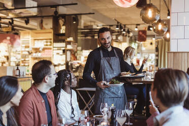 Kellner serviert Essen an multirassische Kunden während einer Party im Restaurant - MASF28410