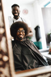 Spiegelung eines lächelnden männlichen Friseurs und eines Kunden im Friseursalon - MASF28420