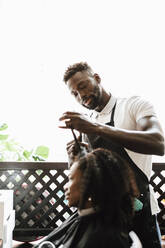 Männlicher Friseur, der einer Kundin im Friseursalon die Haare schneidet - MASF28423