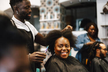 Männlicher Friseur, der einer glücklichen Kundin im Salon die Haare schneidet - MASF28442