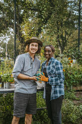 Portrait of smiling female and male farmers standing in garden - MASF28517
