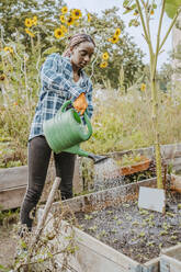 Junge Freiwillige beim Gießen von Pflanzen in einer städtischen Farm - MASF28536