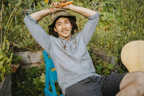 Portrait of male farmer sitting in community garden - MASF28606