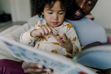 Girl counting number on fingers with father at home - MASF28639