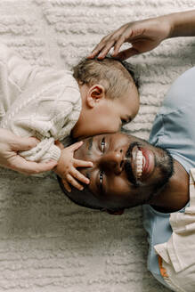 Male toddler kissing father lying on blanket at home - MASF28658