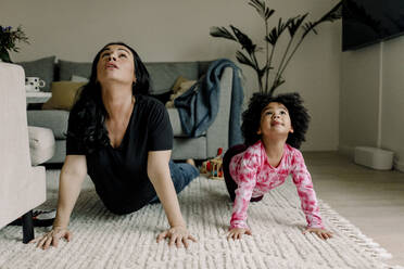 Mutter und Tochter üben Yoga im Wohnzimmer zu Hause - MASF28671