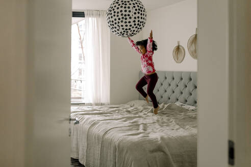Fröhliches Mädchen springt auf dem Bett im Schlafzimmer zu Hause - MASF28676