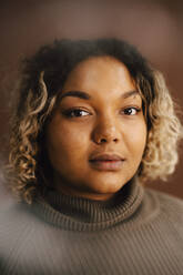 Porträt einer Frau mit Rollkragenpullover vor braunem Hintergrund - MASF28715