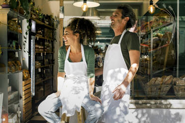 Happy female and male entrepreneurs looking away against cafe - MASF28784