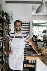 Porträt eines lächelnden männlichen Unternehmers mit Hand auf der Hüfte in einer Bäckerei - MASF28790