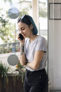 Weibliche Besitzerin, die in einem Friseursalon mit ihrem Smartphone telefoniert - MASF28796