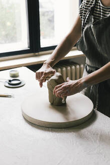 Midsection of female owner kneading clay in workshop - MASF28828