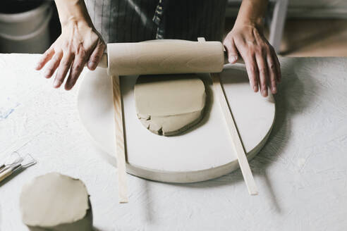 Female owner rolling clay at table in ceramics store - MASF28830