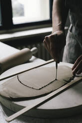 Craftswoman shaping clay at table in ceramics store - MASF28831