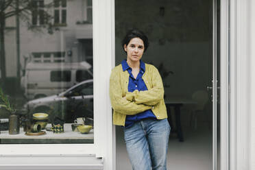 Portrait of female owner with arms crossed standing at entrance of workshop - MASF28852