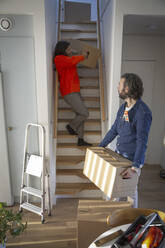 Ältere Frau und Mann tragen Kisten auf den Stufen eines neuen Hauses - MASF28895