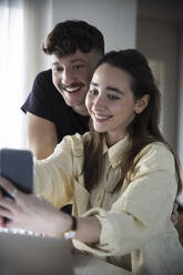Glückliches Paar nimmt Selfie auf Smartphone zu Hause - MASF28912