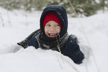 Glücklicher Junge spielt im Schnee im Wald - SEAF00520