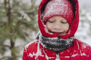 Lächelnder Junge mit Schnee auf Strickmütze und warmer Kleidung im Winter - SEAF00526