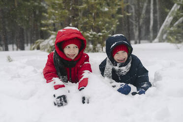 Verspielte Zwillingsbrüder im Schnee liegend im Winter - SEAF00534