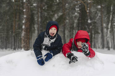 Cheerful twin brothers playing in snowy forest - SEAF00538