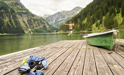 Vorpubertärer Junge springt am Steg in den See - DIKF00624