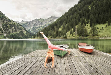 Mädchen, das auf dem Steg am See ein Rad schlägt - DIKF00626