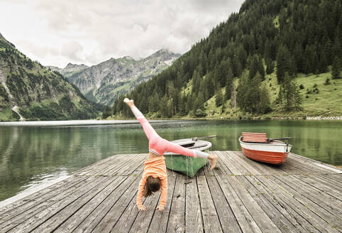 Girl doing cartwheel on jetty by lake - DIKF00626