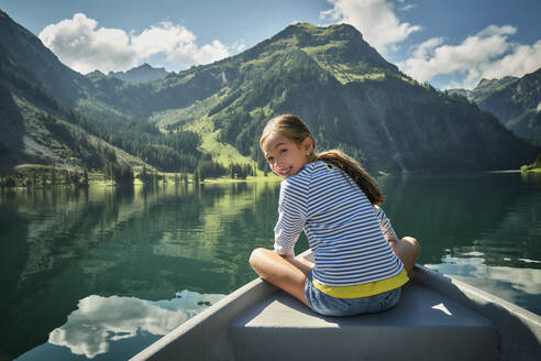 Lächelndes Mädchen sitzt in einem Ruderboot auf einem See - DIKF00629