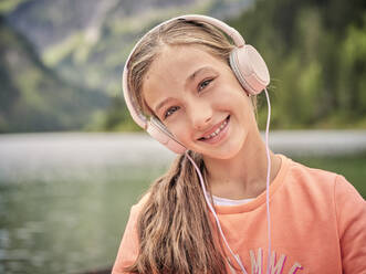 Smiling girl listening music through headphones - DIKF00650