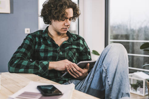 Junger Mann lernt zu Hause am Tablet-PC - UUF25577