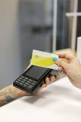 Frau beim kontaktlosen Bezahlen mit Kreditkarte an der Rezeption - MTBF01191