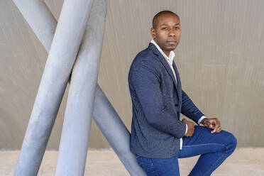 Bald businessman leaning on metallic structure - DLTSF02672